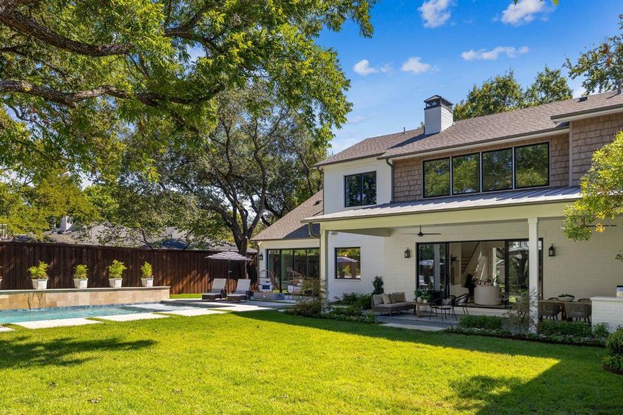 Back of property featuring ceiling fan, a yard, and a patio