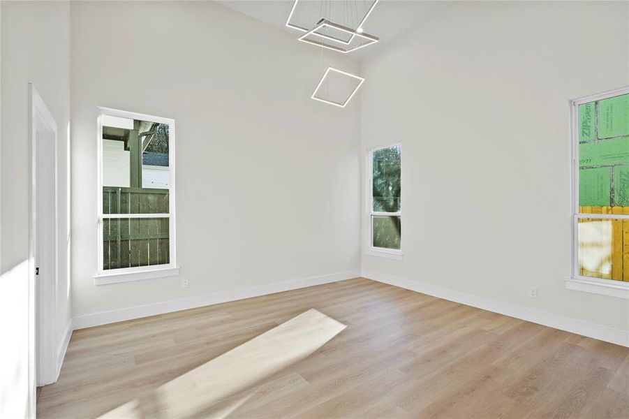 Spare room featuring light wood-style floors, a high ceiling, and baseboards