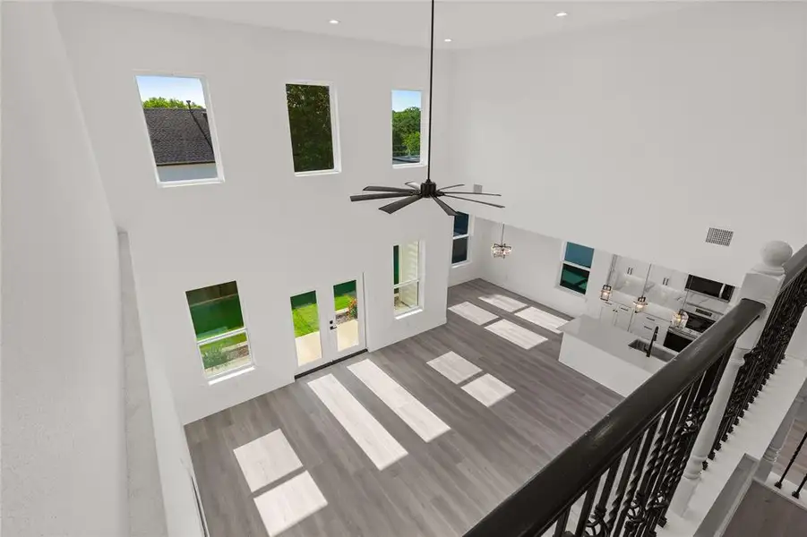 Living room featuring a towering ceiling, wood finished floors, french doors, ceiling fan, and recessed lighting
