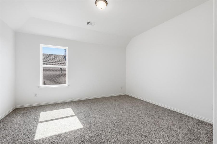 Carpeted spare room with baseboards and lofted ceiling