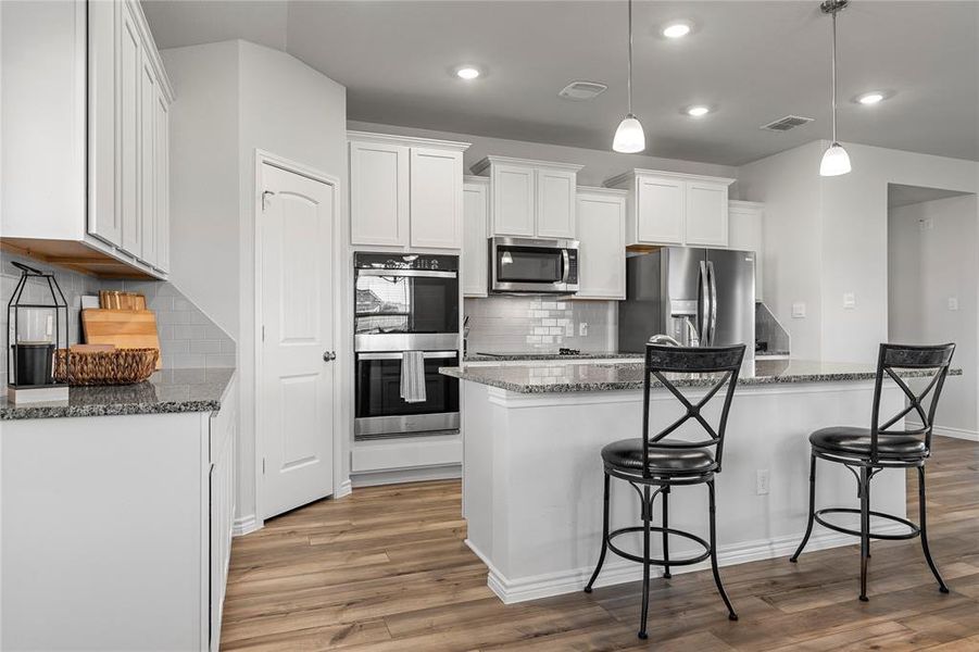 Kitchen with pendant lighting, white cabinetry, dark stone counters, appliances with stainless steel finishes, and recessed lighting