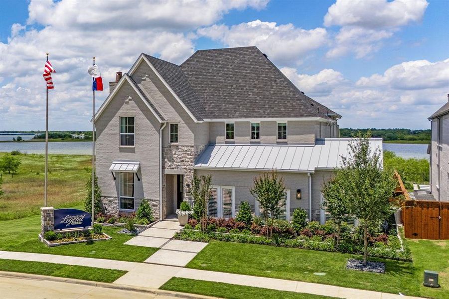 View of front of home with a water view, brick siding, a front lawn, and a chimney View of front of home with a water view, brick siding, a front lawn, and a chimney