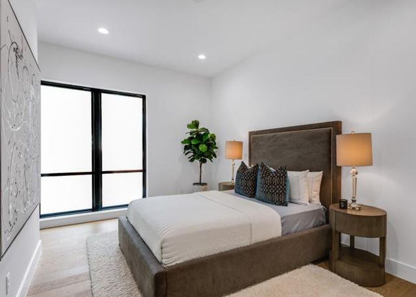 Bedroom with light wood-style flooring, multiple windows, and recessed lighting