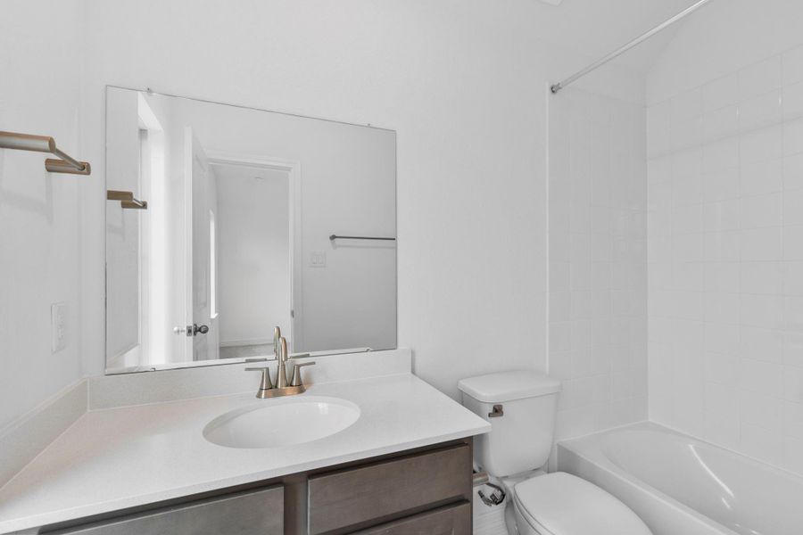 A secondary bathroom featuring classic finishes of the AW Roosevelt Collection, with stained cabinetry and lustrous nickel fixtures.