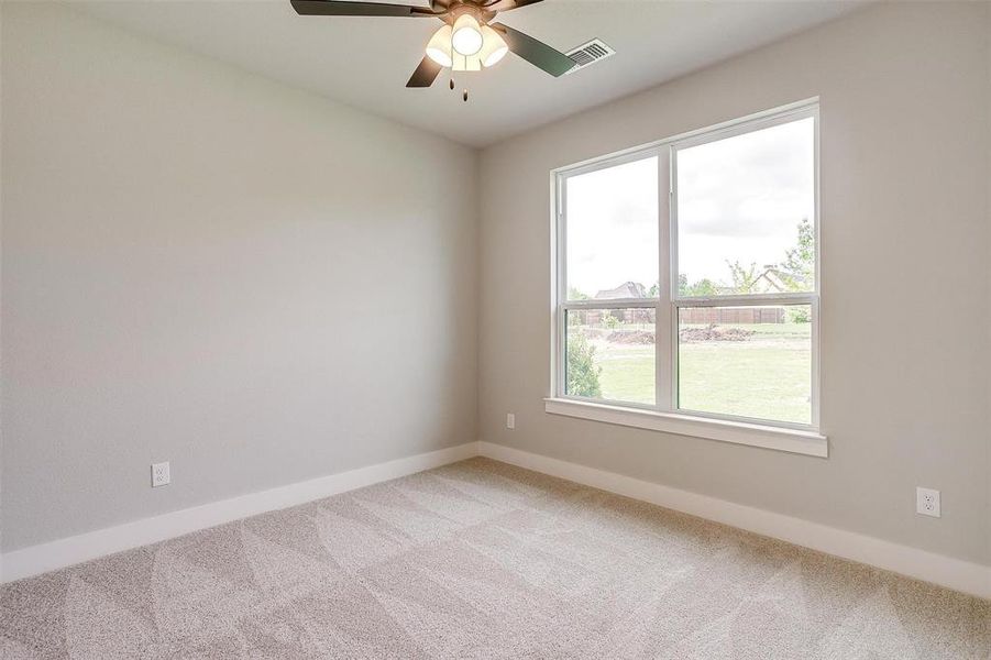 Empty room featuring light colored carpet, baseboards, a ceiling fan, and visible vents Empty room featuring light colored carpet, baseboards, a ceiling fan, and visible vents