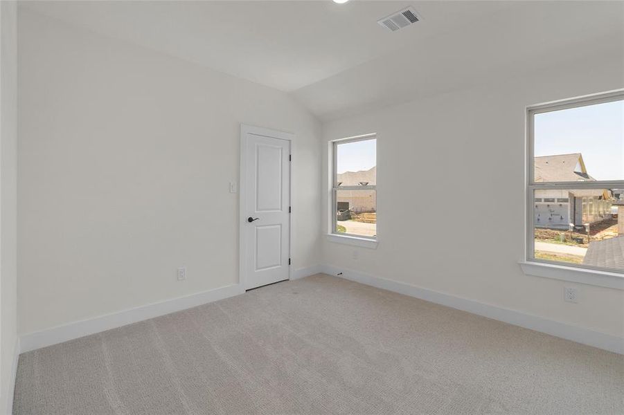 Room featuring light gray carpeting, neutral painted walls, white trim, a two-panel interior door with black hardware, and two windows