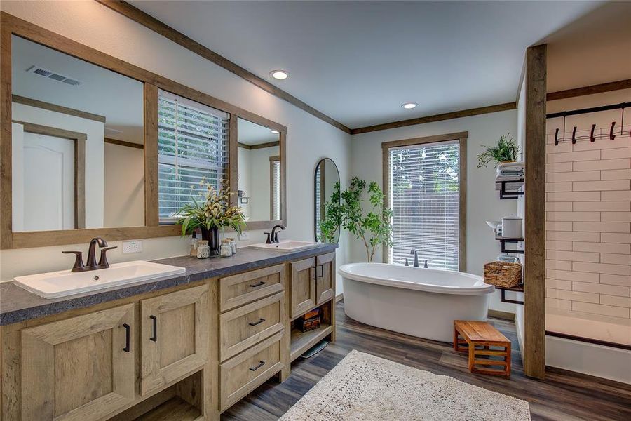 Full bath with soaking tub, double vanity, LVP floors, recessed lighting, and crown molding. Walk-in closet is in ensuite bath.
