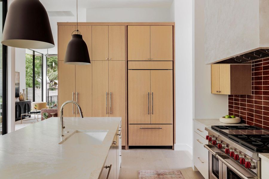 Kitchen featuring high quality appliances, backsplash, light wood-type flooring, and light stone countertops Kitchen featuring high quality appliances, backsplash, light wood-type flooring, and light stone countertops