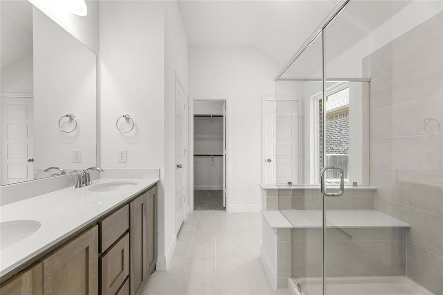 Bathroom with tile floors, a shower with door, lofted ceiling, and double sink vanity