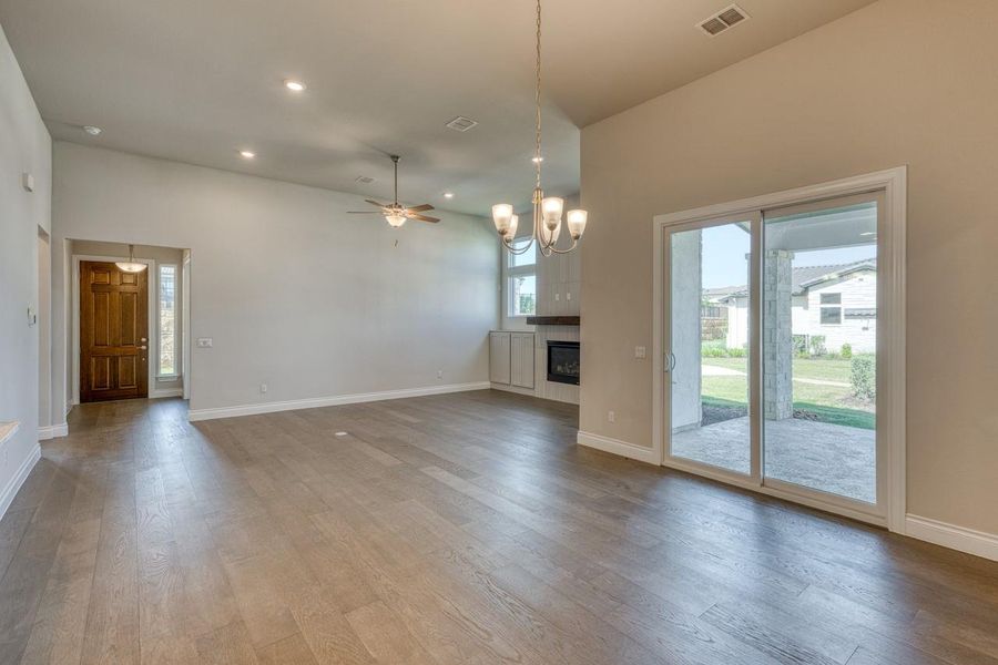 Unfurnished living room with recessed lighting, a chandelier, ceiling fan, a glass covered fireplace, and wood finished floors