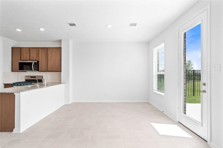 Start your day with a warm cup of coffee and quality time in this charming dining area! Highlights include a large window with blinds, custom neutral paint, ceramic tile flooring, recessed lighting, high ceilings, and a convenient door leading to the rear patio and backyard. Start your day with a warm cup of coffee and quality time in this charming dining area! Highlights include a large window with blinds, custom neutral paint, ceramic tile flooring, recessed lighting, high ceilings, and a convenient door leading to the rear patio and backyard.