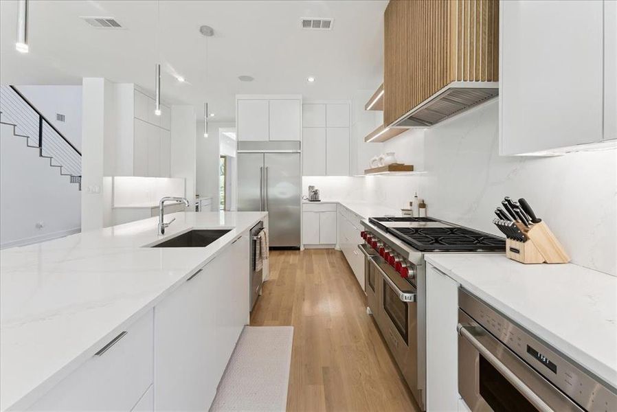 Kitchen featuring modern cabinets, white cabinetry, open shelves, premium appliances, and light wood-type flooring