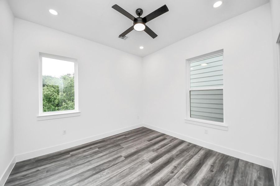 This room features modern vinyl flooring, fresh white walls, and recessed lighting. It has two large windows for ample natural light and a ceiling fan for comfort. Perfect for a bedroom or home office. This room features modern vinyl flooring, fresh white walls, and recessed lighting. It has two large windows for ample natural light and a ceiling fan for comfort. Perfect for a bedroom or home office.