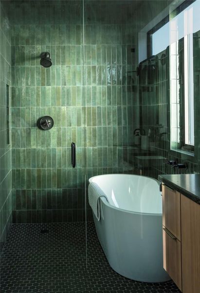 Spa-inspired bathroom featuring floor-to-ceiling green tile, soaking tub, walk-in shower, and modern matte black fixtures.