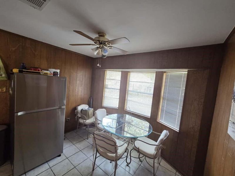 Dining area with wood walls, light tile patterned floors, and ceiling fan Dining area with wood walls, light tile patterned floors, and ceiling fan