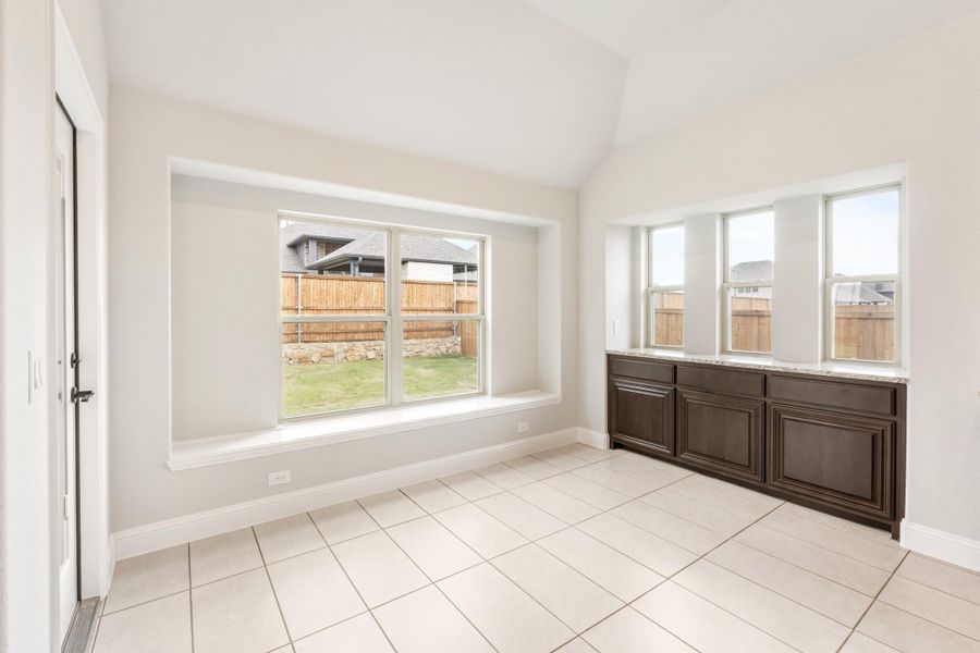 Bright dining area with tile floors, dark wood buffet cabinet, and large windows overlooking backyard Bright dining area with tile floors, dark wood buffet cabinet, and large windows overlooking backyard