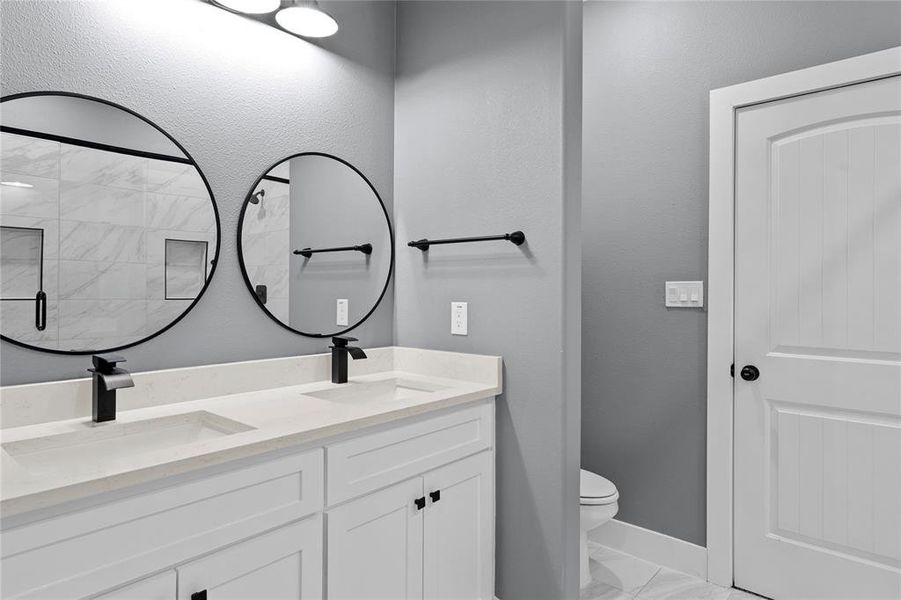 Full bath featuring double vanity, light marble finish flooring, a stall shower, and a textured wall Full bath featuring double vanity, light marble finish flooring, a stall shower, and a textured wall