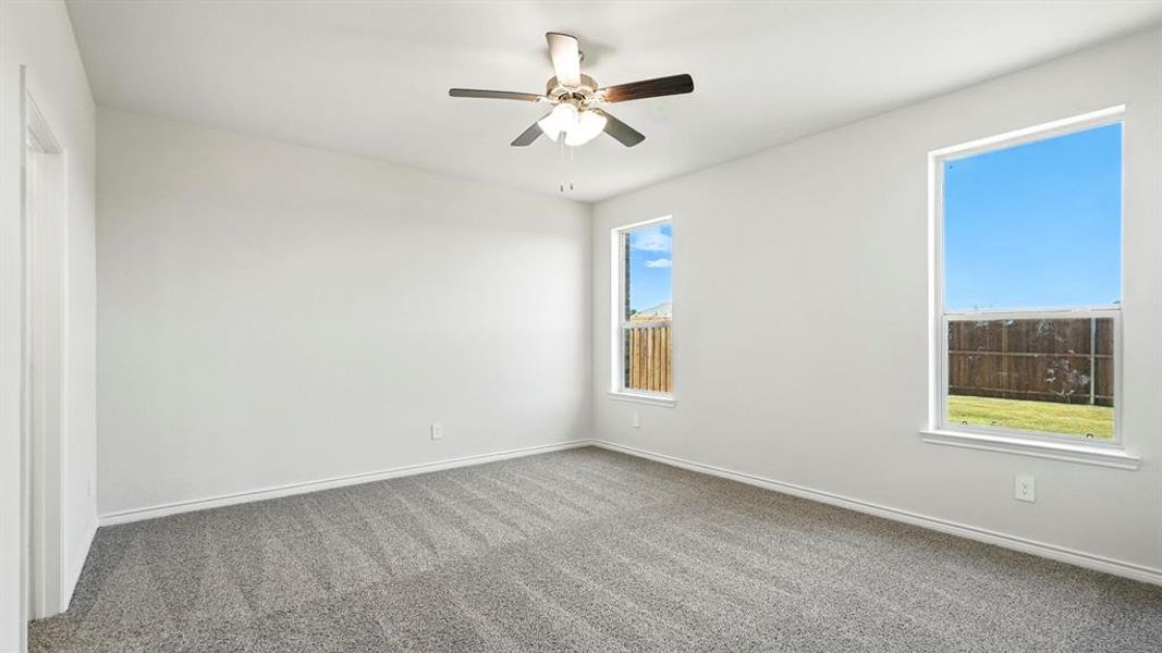 Spacious room featuring light gray carpeting, neutral wall finishes, and a ceiling fan with integrated lighting
