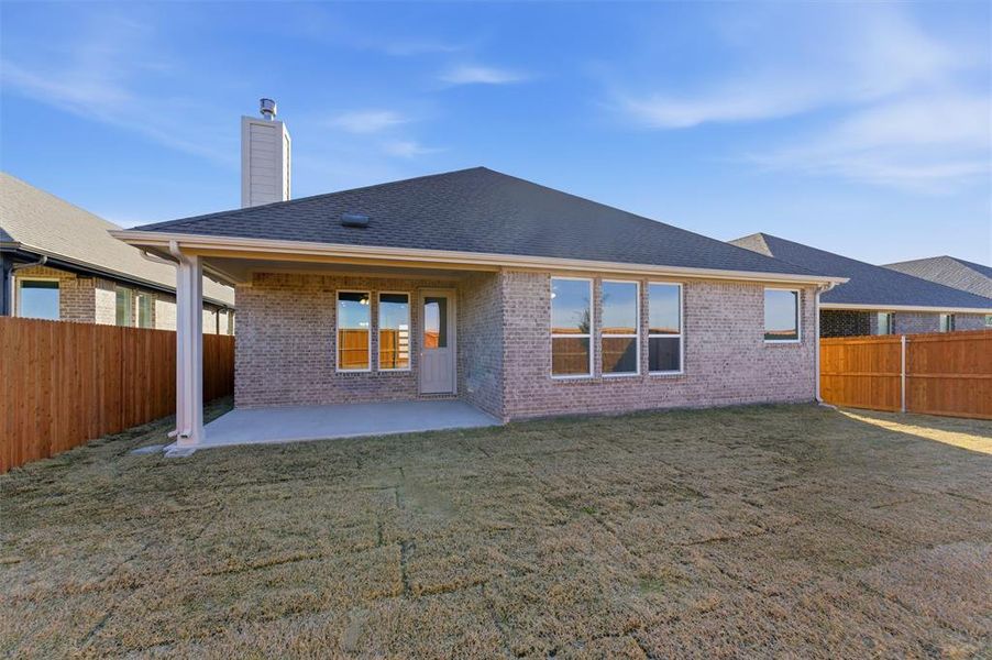 Rear view of property featuring a patio, a chimney, a fenced backyard, brick siding, and a shingled roof