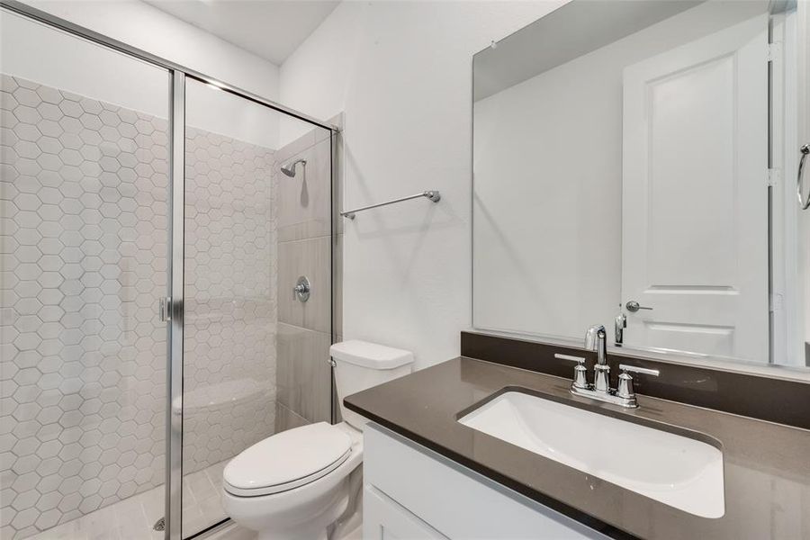 Bathroom with a shower with door, vanity, and toilet