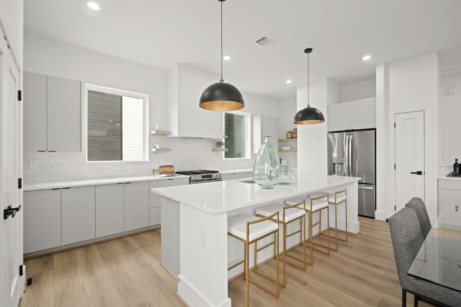 Step into the thoughtfully designed kitchen where function meets style. At the center is an island with Quartz counter, a breakfast bar and a large stainless steel sink, perfect for quick meals and casual conversations.
