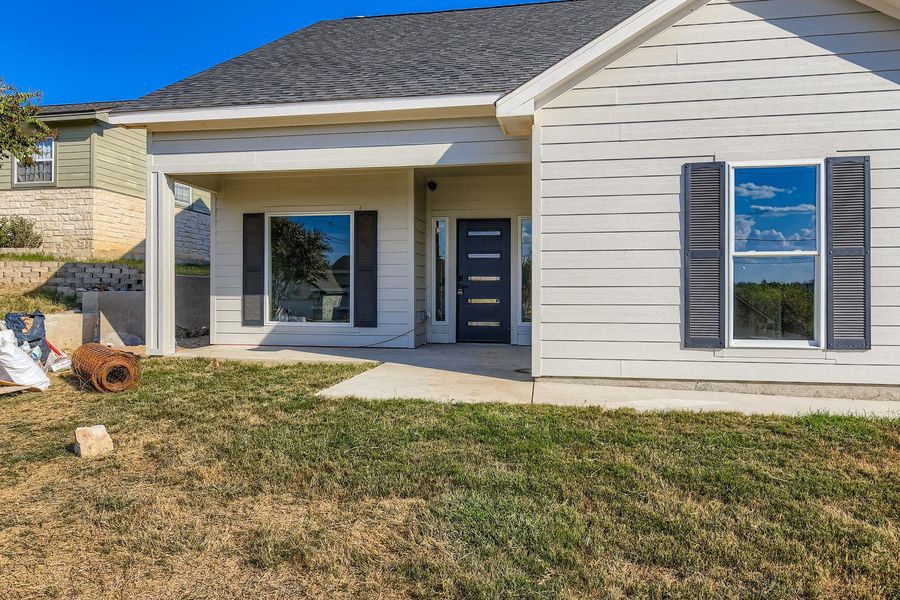 View of exterior entry with a yard and roof with shingles