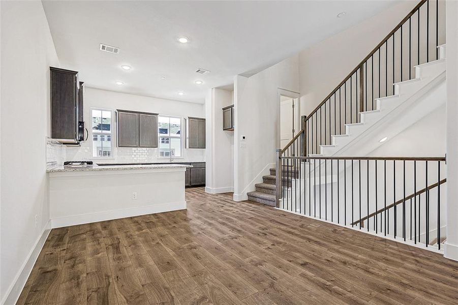 Kitchen with a peninsula, dark wood-style flooring, dark brown cabinets, recessed lighting, and backsplash