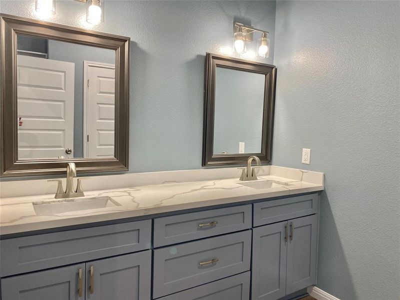 Two individual vanities featuring sleek counters and modern fixtures define this primary bathroom. Two individual vanities featuring sleek counters and modern fixtures define this primary bathroom.