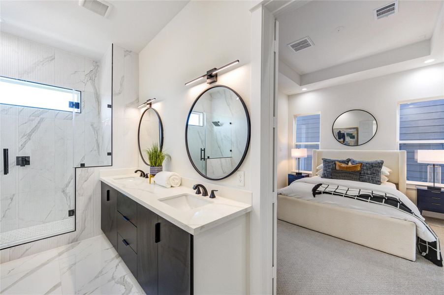 Primary bathroom featuring double vanity sinks with quartz countertops, adjustable anti-fog mirrors, and tile flooring. Highlights include 10-ft ceilings, a freestanding soaking tub, chandelier accent lighting, and a frameless shower with floor-to-ceiling tile.