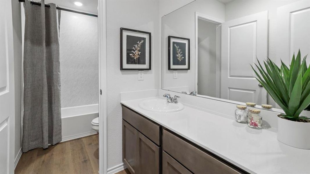 Bathroom featuring dark wood-type flooring, vanity, and shower / tub combo