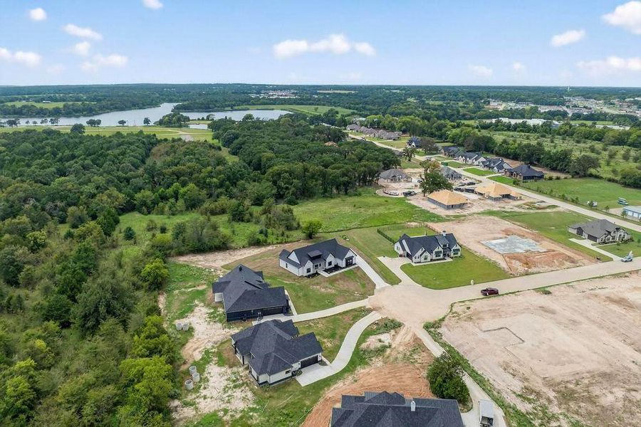 Aerial view of residential area with a nearby body of water and a forest Aerial view of residential area with a nearby body of water and a forest