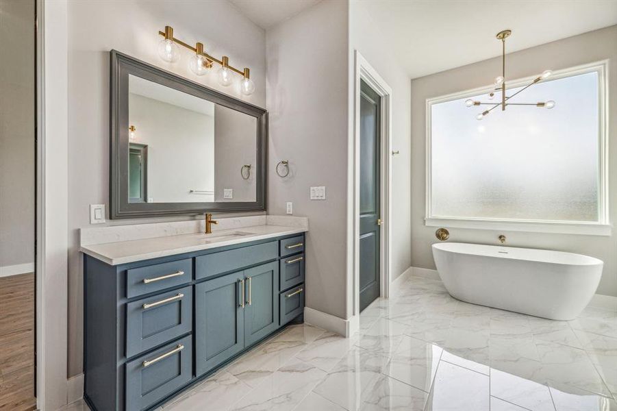 Bathroom featuring tile patterned flooring, a notable chandelier, and vanity