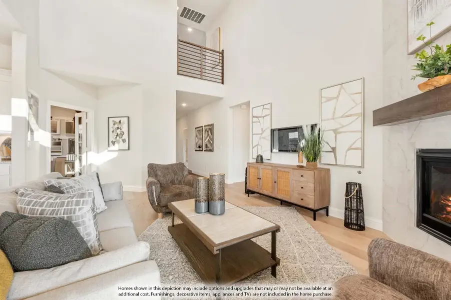 Open-concept living room with two-story ceiling, marble fireplace, and second-floor balcony overlook