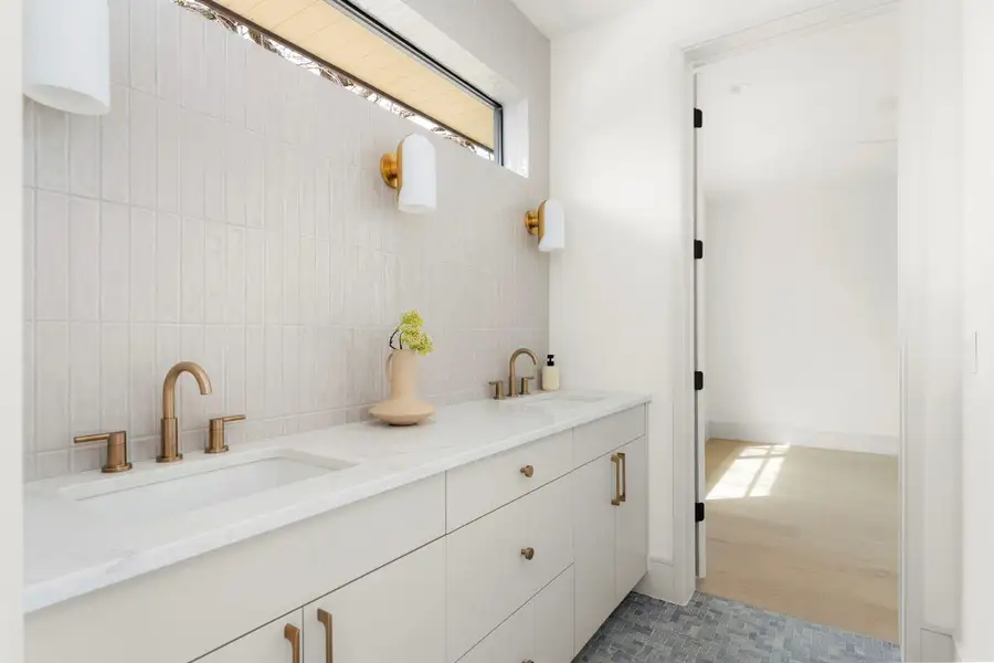 Full bathroom featuring double vanity and decorative backsplash