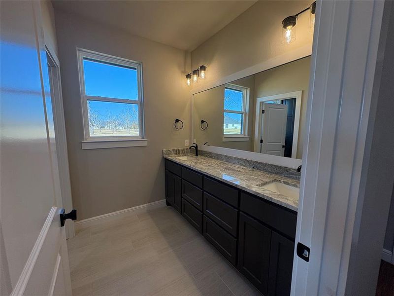 Full bath with double vanity and baseboards