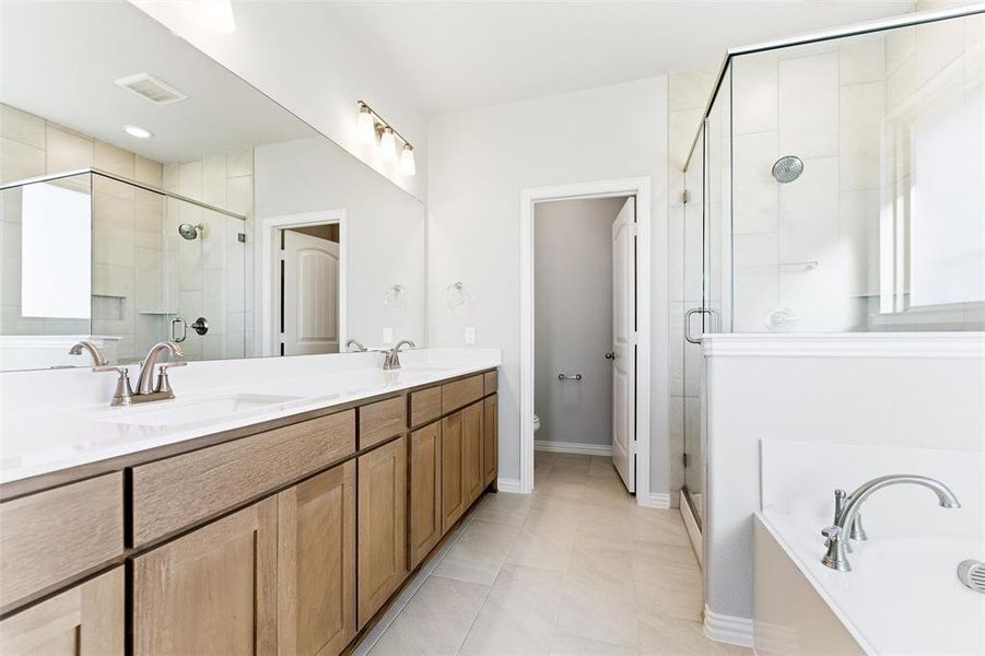 Bathroom featuring double vanity, a bath, a shower stall, and light tile patterned flooring
