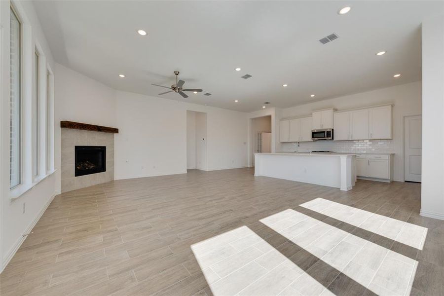 Unfurnished living room featuring ceiling fan and a tile fireplace