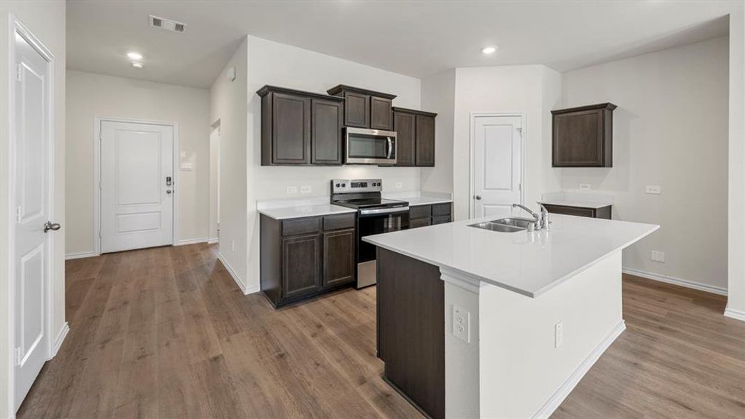 Kitchen with stainless steel appliances, dark wood finish cabinets, a kitchen island with sink, recessed lighting, and dark wood-style flooring