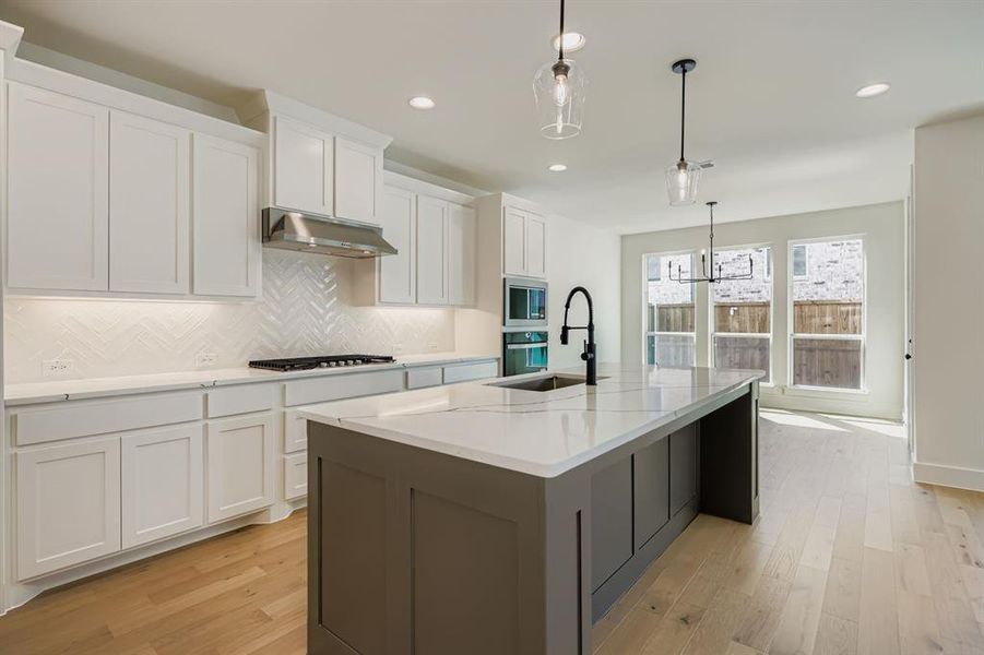 Kitchen with white cabinets, decorative backsplash, decorative light fixtures, light wood-style floors, and recessed lighting