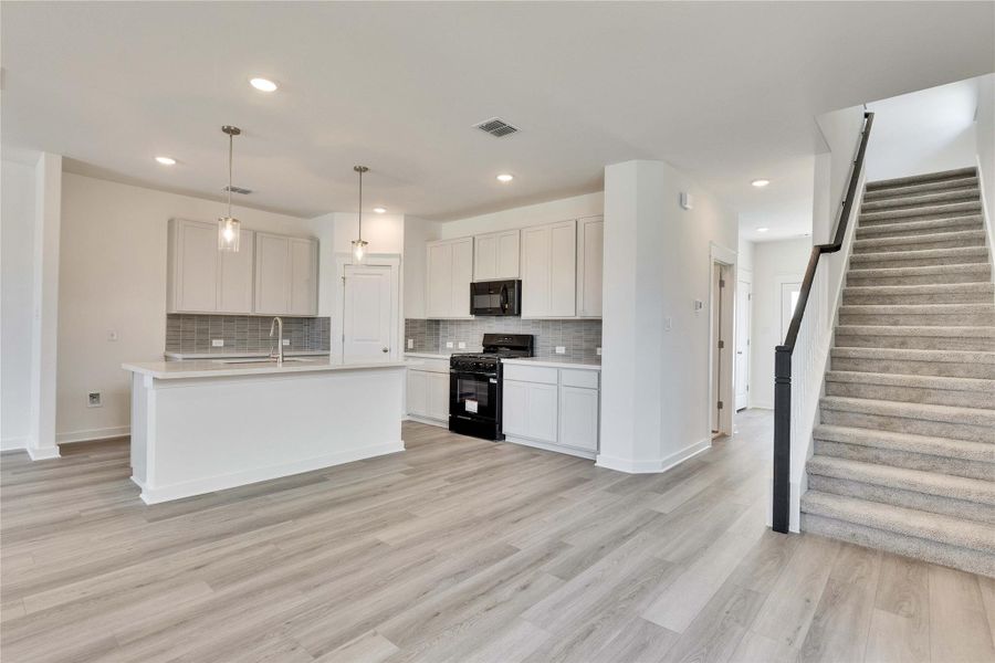 Kitchen with black appliances, decorative light fixtures, white cabinets, tasteful backsplash, and recessed lighting Kitchen with black appliances, decorative light fixtures, white cabinets, tasteful backsplash, and recessed lighting