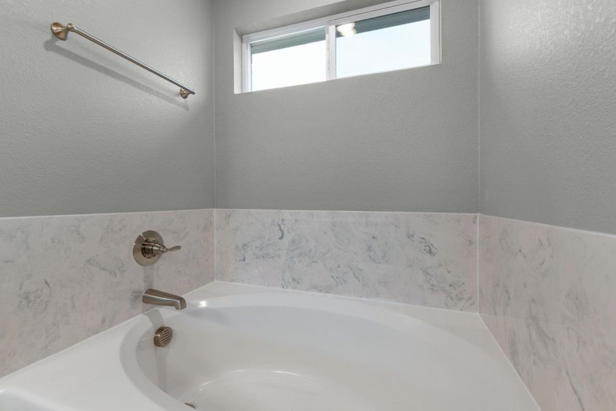 Indulge in relaxation with this inviting soaking tub, complemented by elegant tile surround and natural light.
