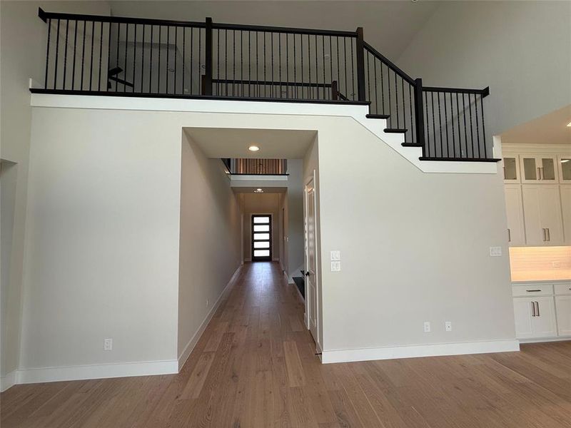 Hallway with a towering ceiling, light wood-style flooring, and recessed lighting Hallway with a towering ceiling, light wood-style flooring, and recessed lighting