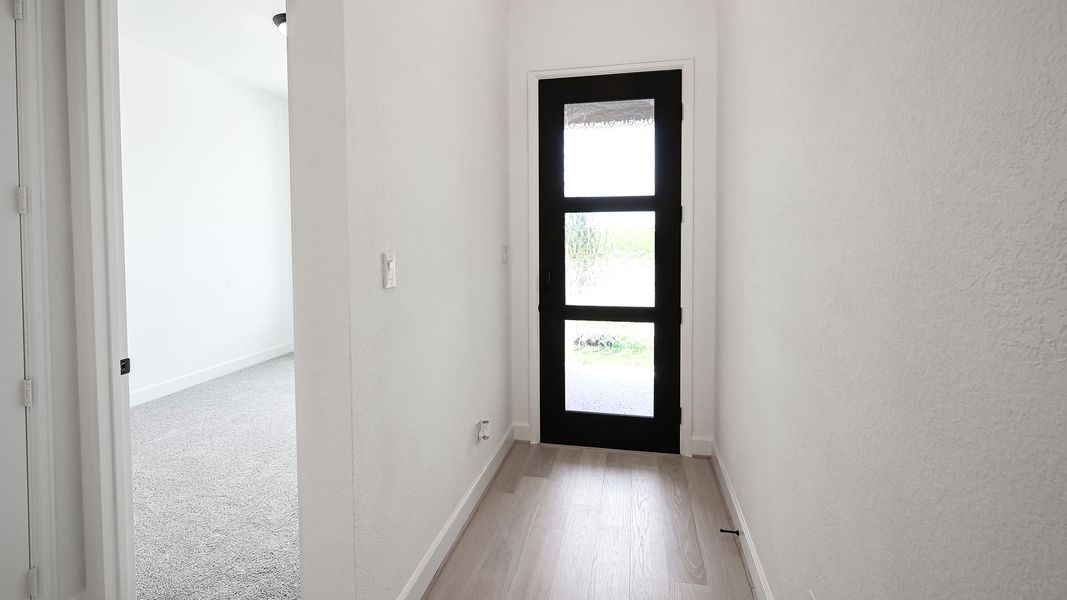 Foyer featuring light wood-style floors and a textured wall Foyer featuring light wood-style floors and a textured wall