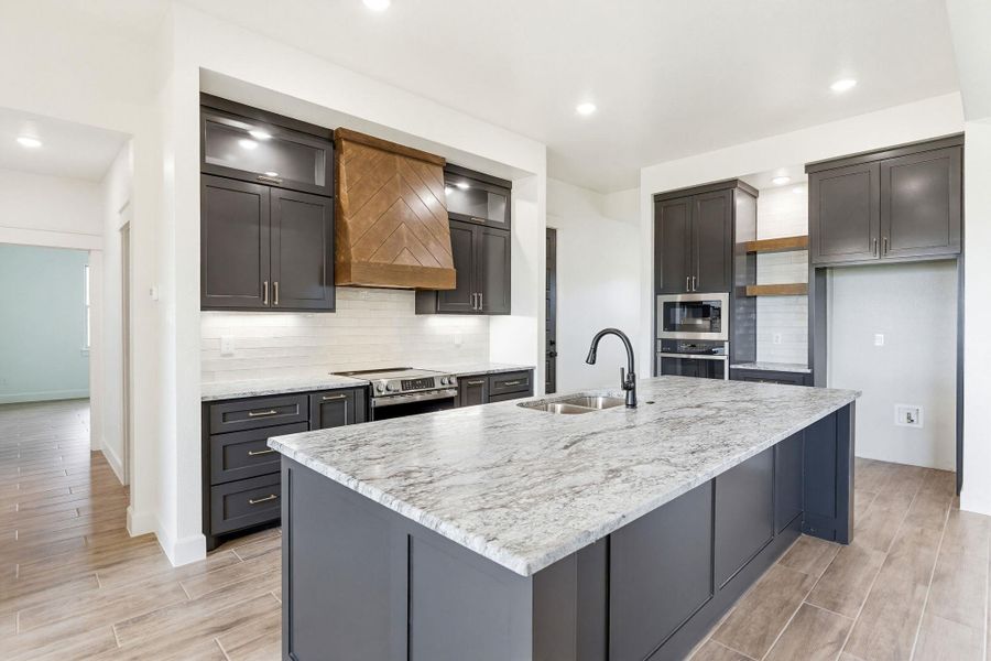 A contemporary kitchen showcasing rich cabinetry, sleek appliances, and a grand central island. A contemporary kitchen showcasing rich cabinetry, sleek appliances, and a grand central island.