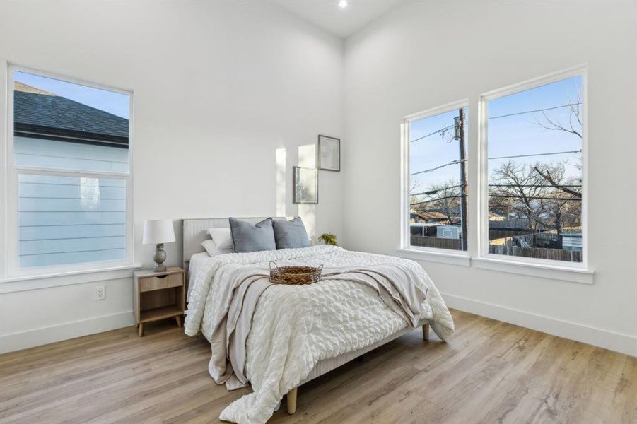 Bedroom with light wood-type flooring and a towering ceiling