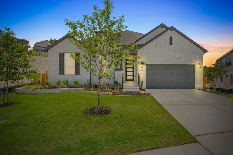 View of front of house featuring brick siding, driveway, a front yard, and a garage