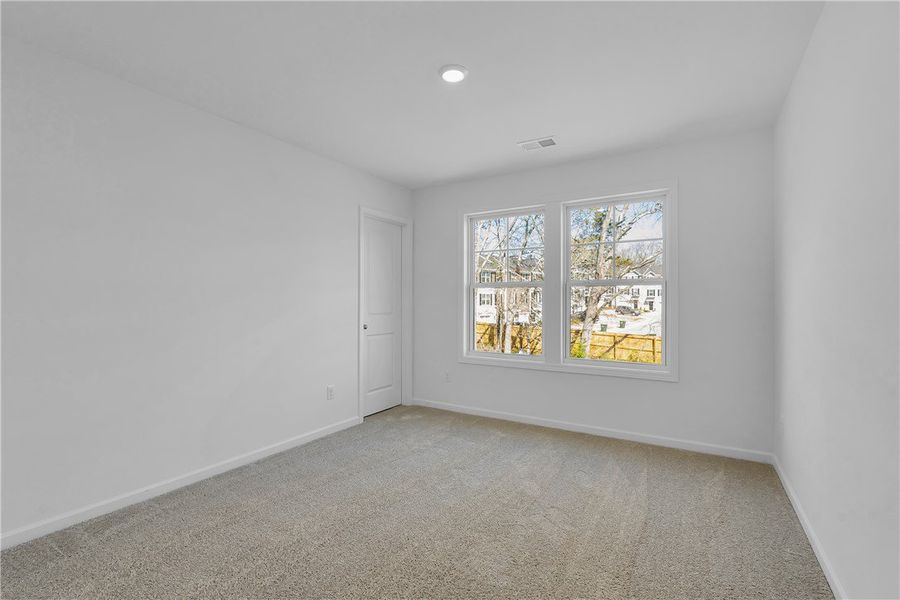 This bright bedroom offers comfortable carpeting a