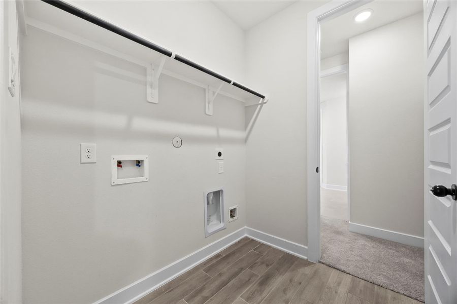 This photo shows a clean, well-lit laundry room with hookups for a washer and dryer, a built-in shelf, and attractive flooring. This photo shows a clean, well-lit laundry room with hookups for a washer and dryer, a built-in shelf, and attractive flooring.