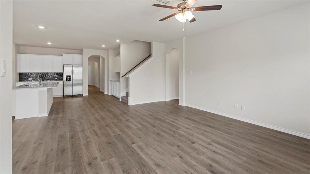 Unfurnished living room with arched walkways, light wood-style flooring, stairs, recessed lighting, and a ceiling fan Unfurnished living room with arched walkways, light wood-style flooring, stairs, recessed lighting, and a ceiling fan