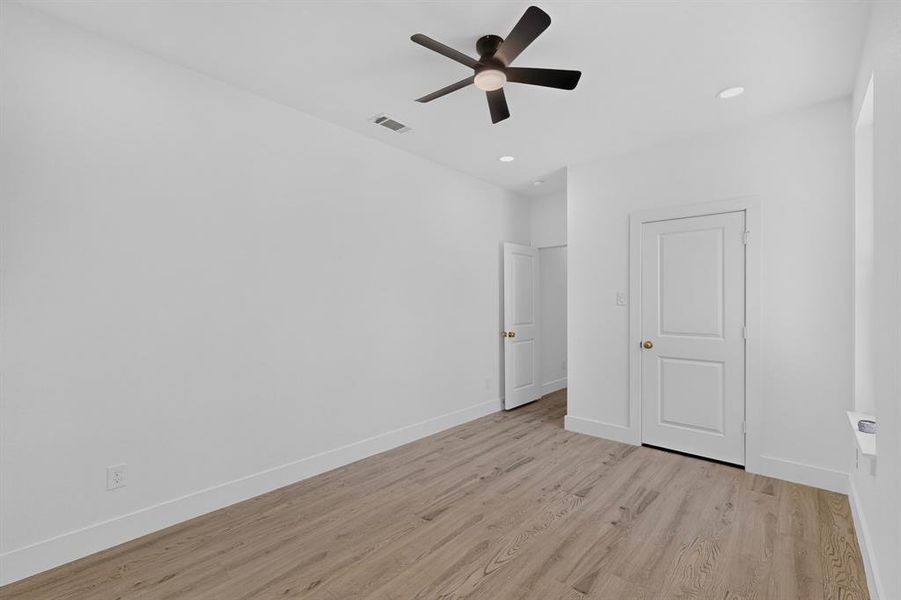 Room featuring wood-finish flooring, white walls, and a contemporary ceiling fan